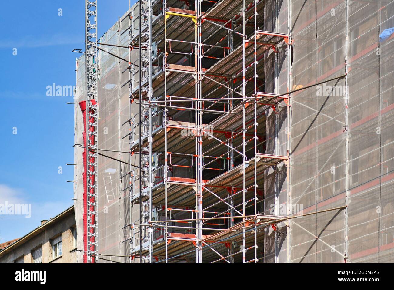 Part of construction site with scaffolding on multistory building facade during renovation Stock Photo