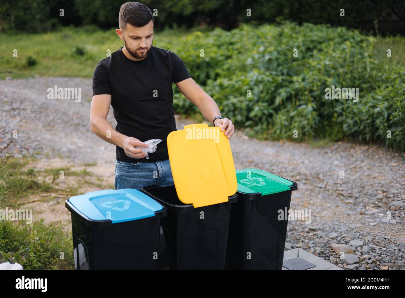 Man throwing plastic bag into recycling bin on back yard. Different