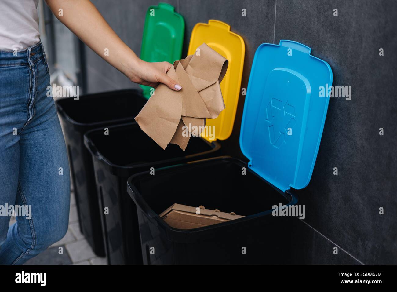 Closeup of female throwing piece of cardboard in recycling bin