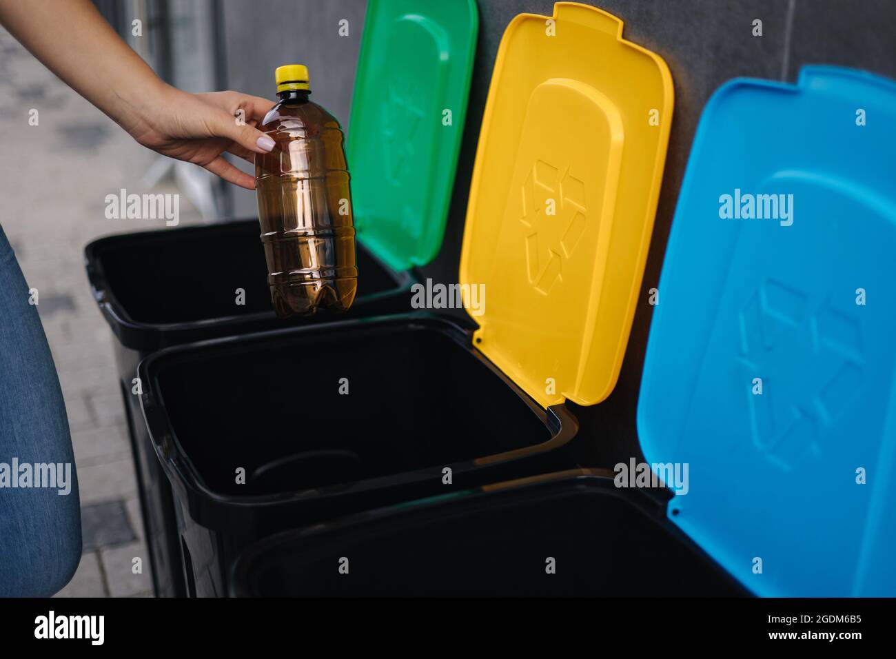 Closeup of female throwing plastic bottle in recycling bin. Different