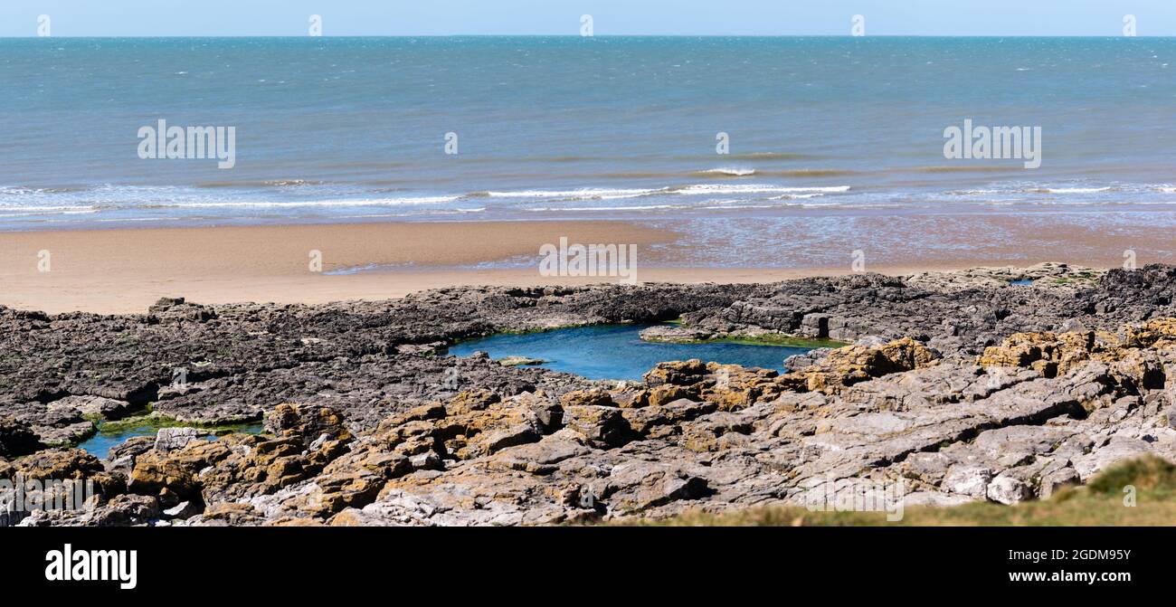 Panoramic view of a beach with rock pools in the foreground Stock Photo