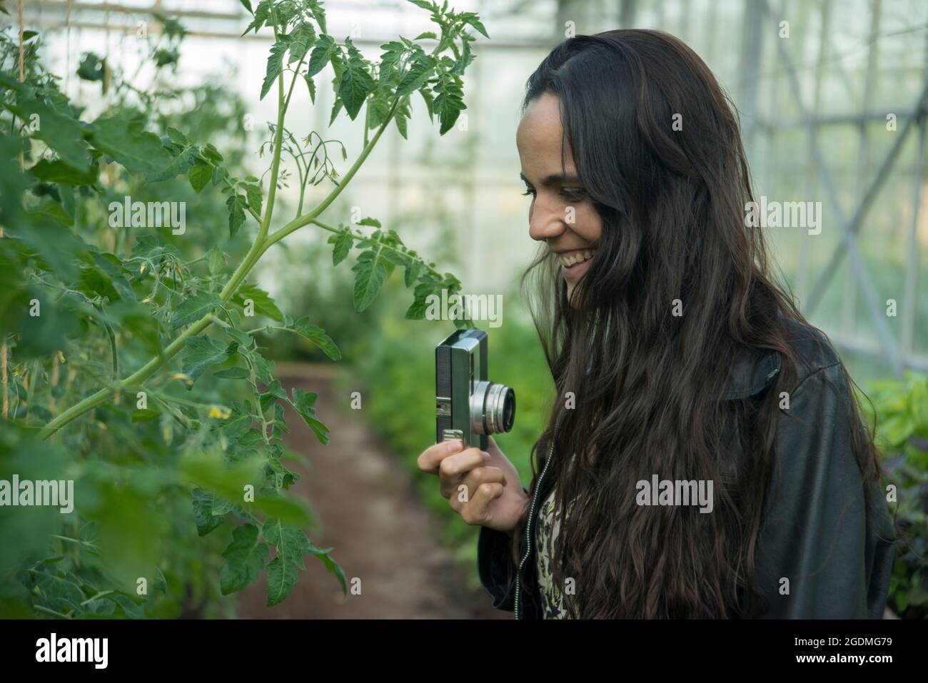 Woman with old camera in greenhouse Stock Photo