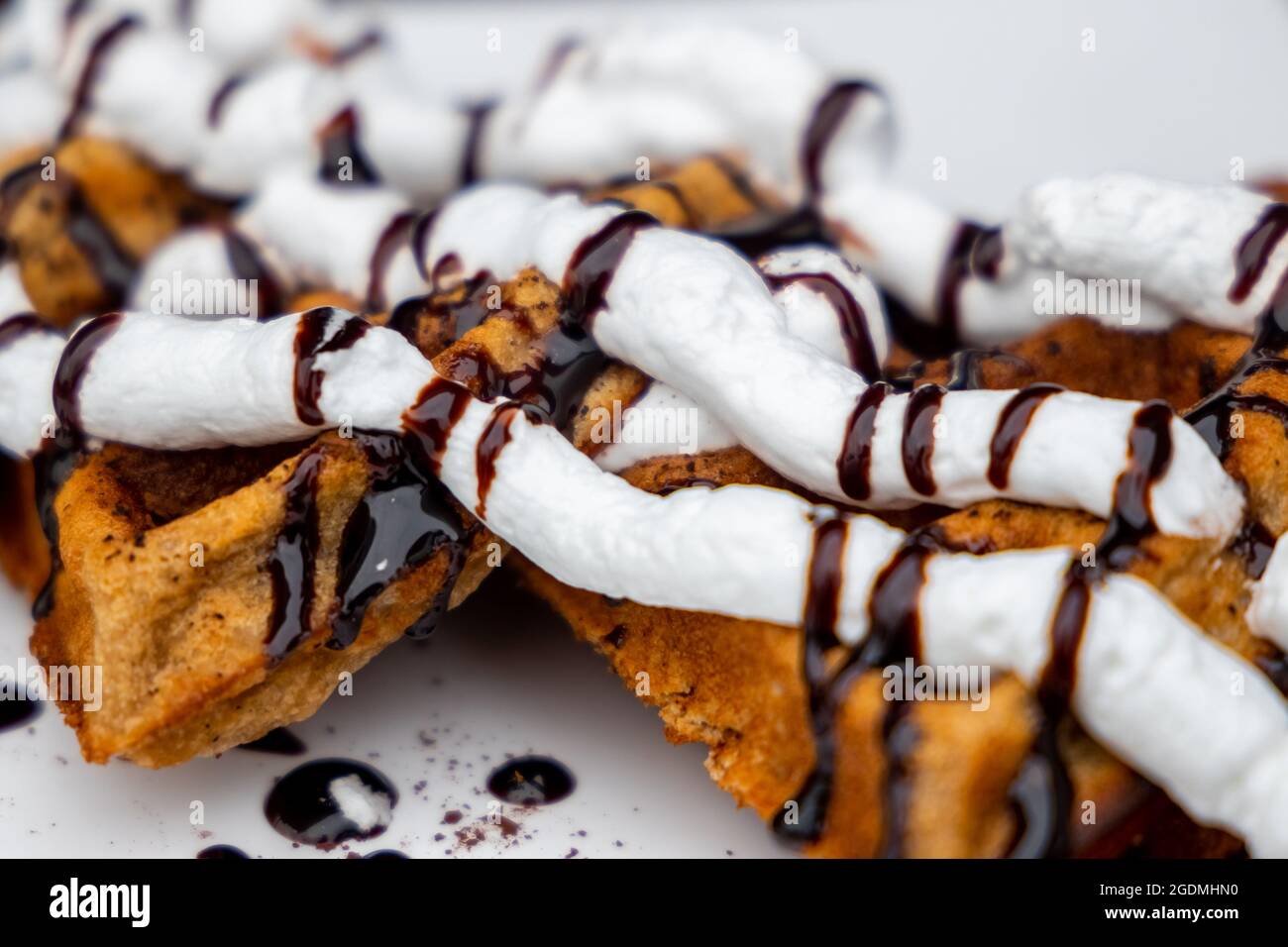 Waffles Closeup. Decorated Belgian Waffles with Whipped Creme and Chocolate Syrup ready to be served and consumed. selective focus Stock Photo