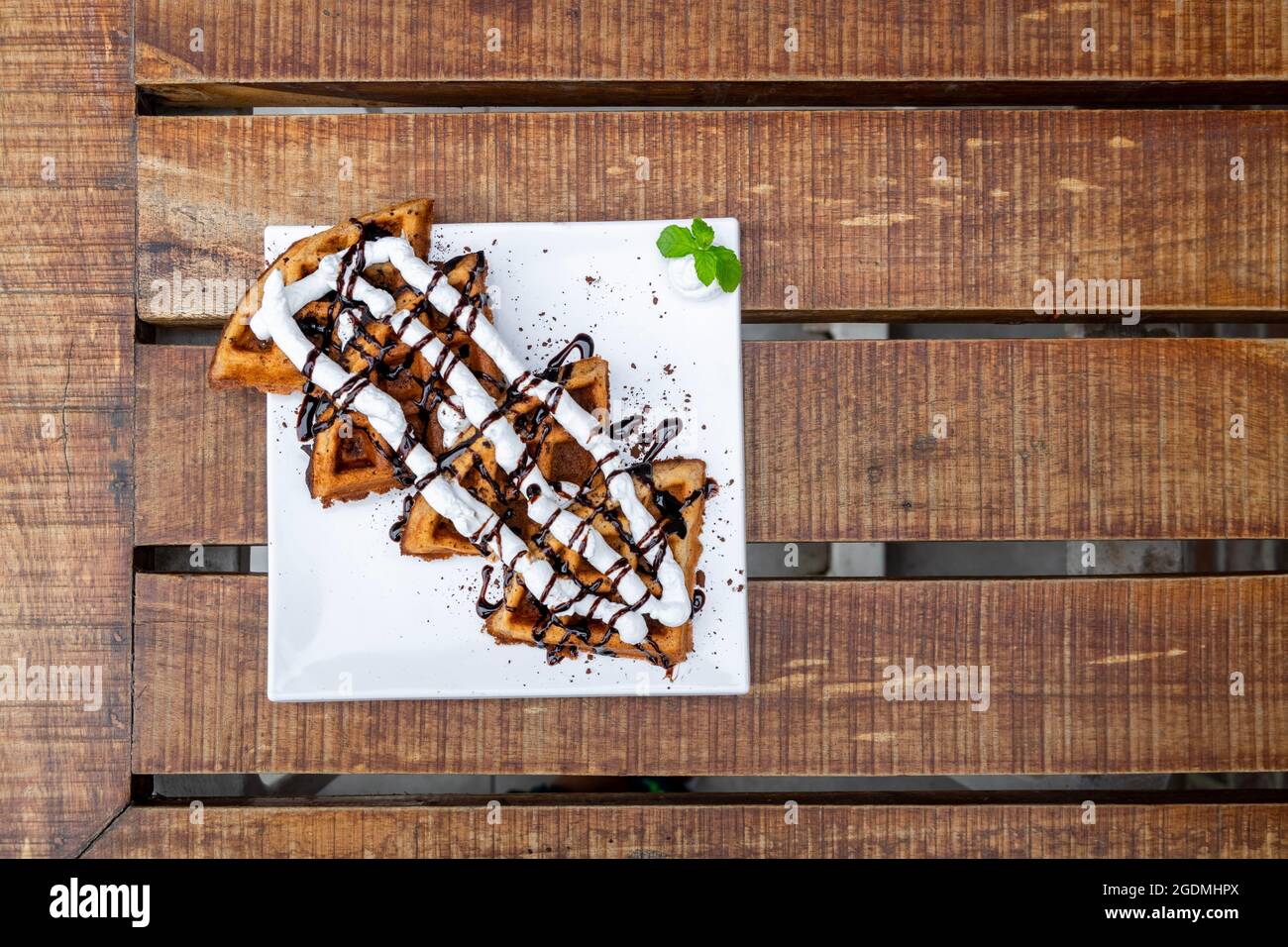 Waffles Closeup. Decorated Belgian Waffles with Whipped Creme and Chocolate Syrup ready to be served and consumed. selective focus Stock Photo