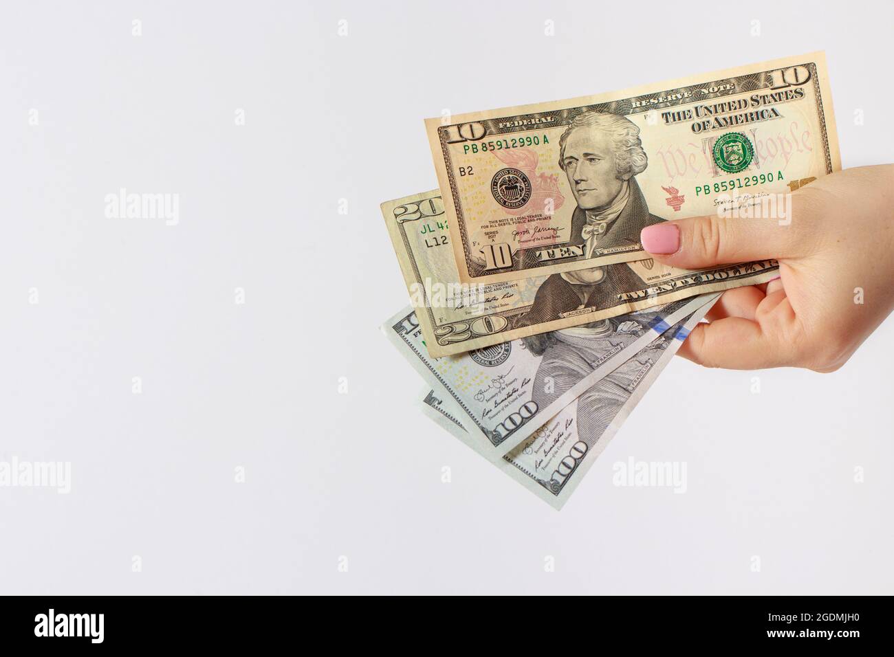A woman's hand holds many dollar bills on a white with place for text copy space banner. Credit, corruption, borrowing money and financial literacy Stock Photo