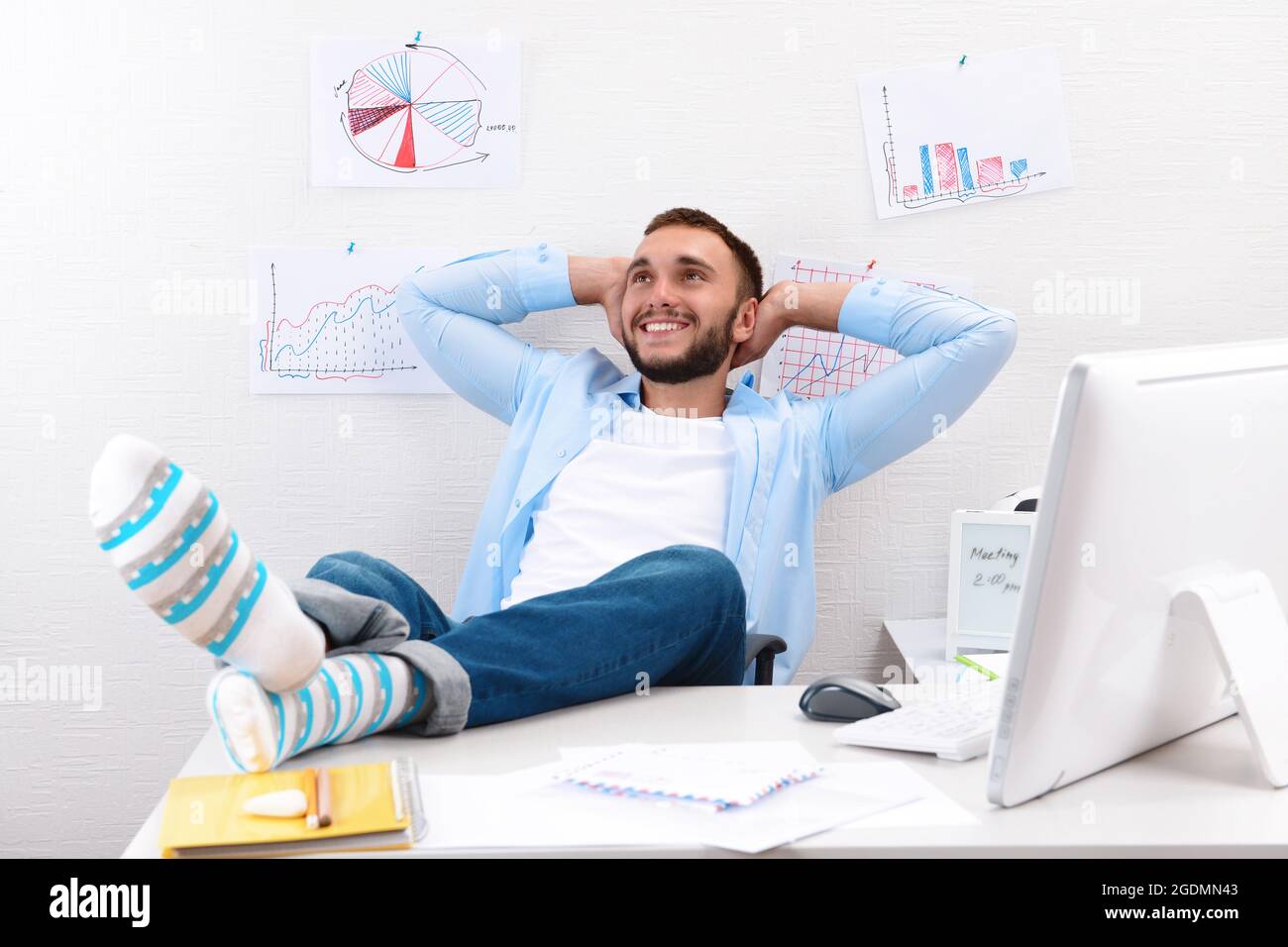 Confident businessman holding his legs in funny socks on desk Stock ...