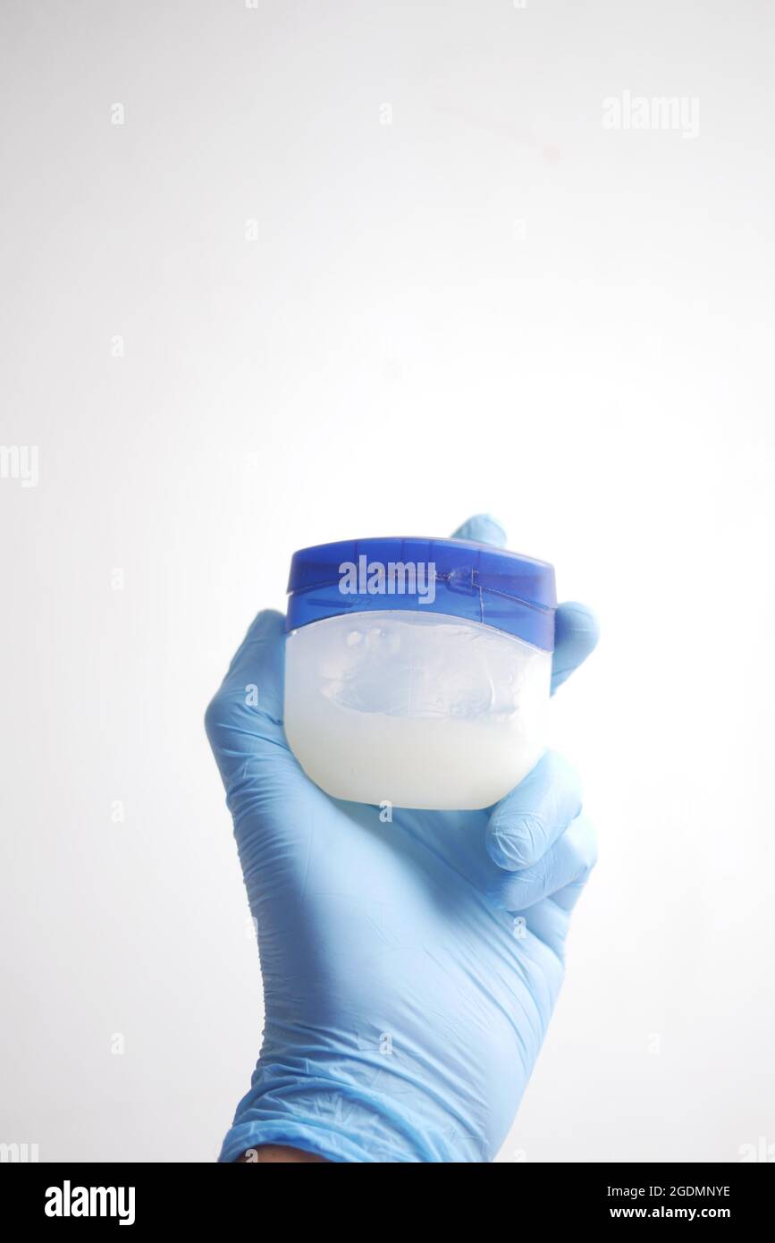 hand in latex gloves holding petroleum jelly on white background Stock Photo Alamy