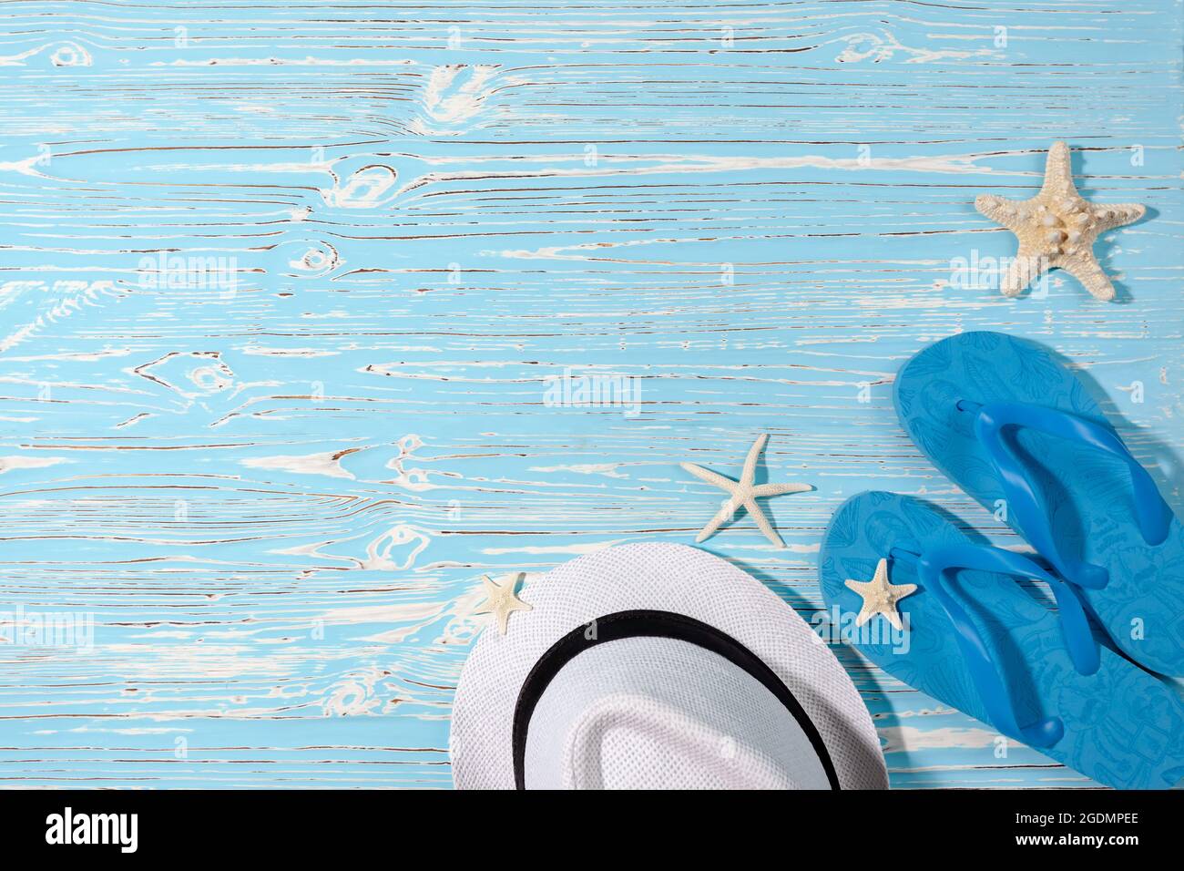 straw white hat, blue rubber flip flops and starfish on a blue wooden ...