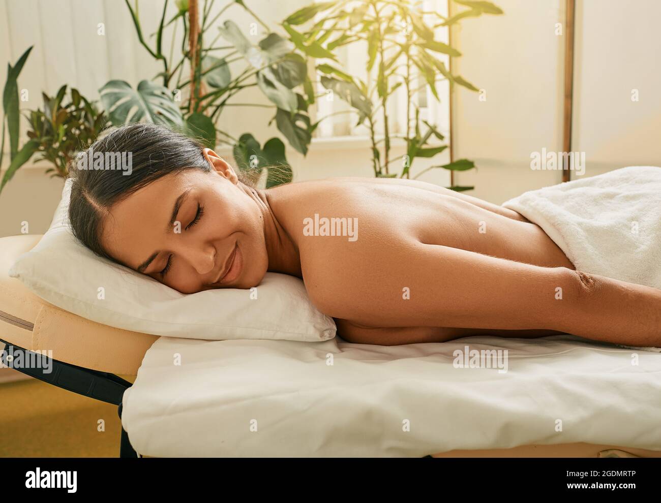 massage therapy and body care.Young woman enjoys massage at spa. Relaxing back and body massage at wellness. Time of rela Stock Photo