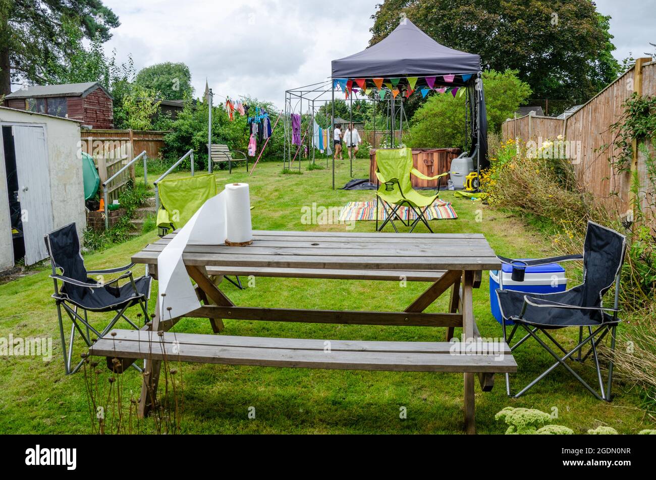 A garden set up for entertaining with a wooden table and bench set in the foregrounnd rented hot tub under a gazebo behind. Stock Photo
