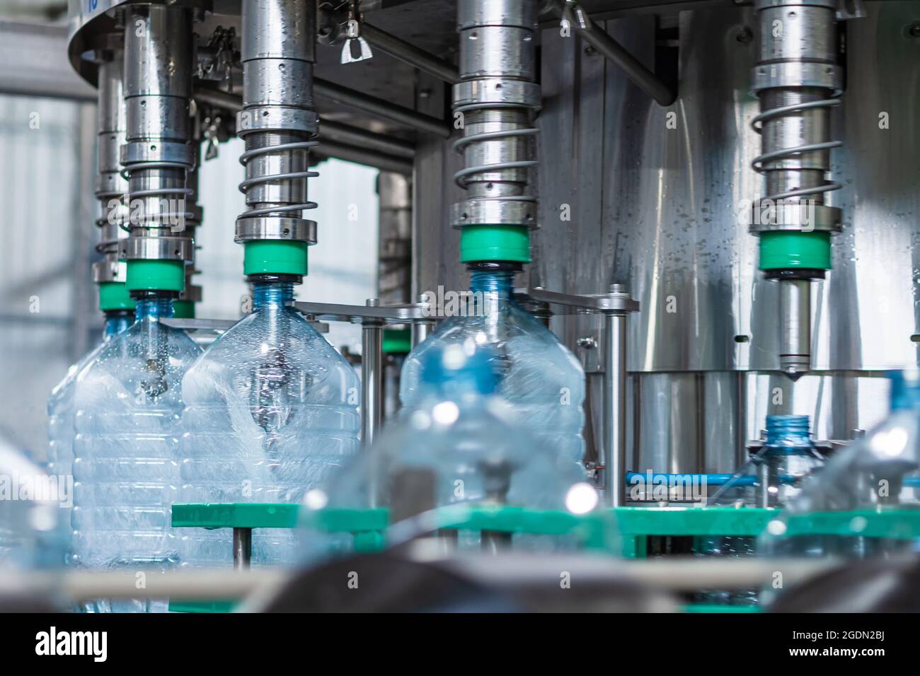 Automated line for bottling drinking water in five-liter plastic bottles. The process of filling the bottle in an automatic filling machine. Food prod Stock Photo