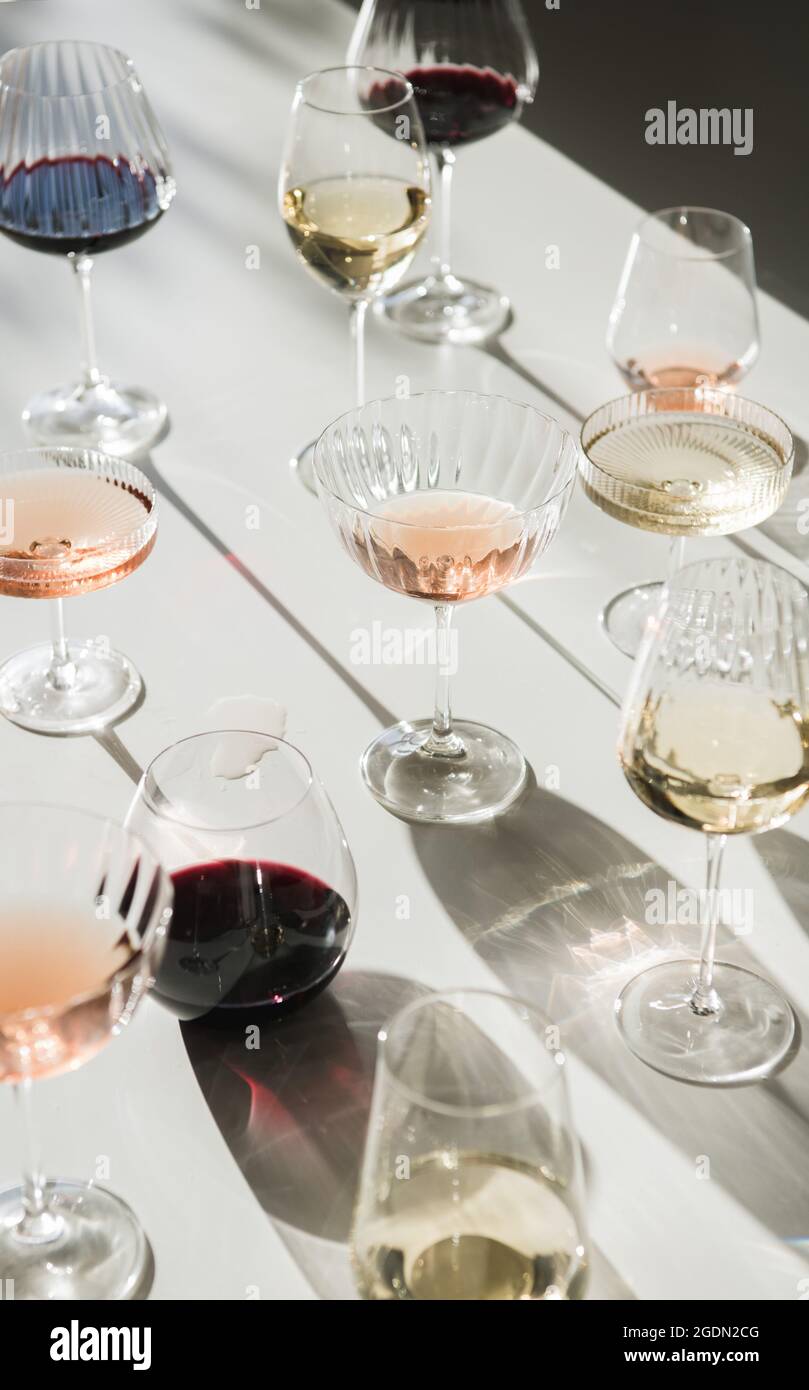 Glasses of red, rose and white wine on white background with shades ...