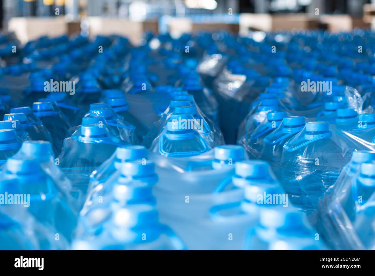 Blue five-liter plastic water bottles packed at the warehouse of finished products. Food production Stock Photo