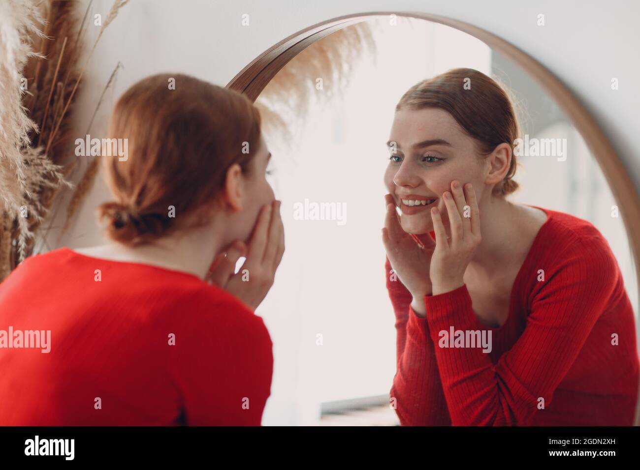 Young beautiful woman standing front of mirror in living room. Stock Photo