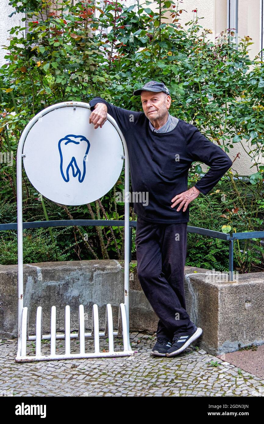 Elderly senior man leaning on Bike stand outside dental practice in Schöneberg,Berlin Stock Photo