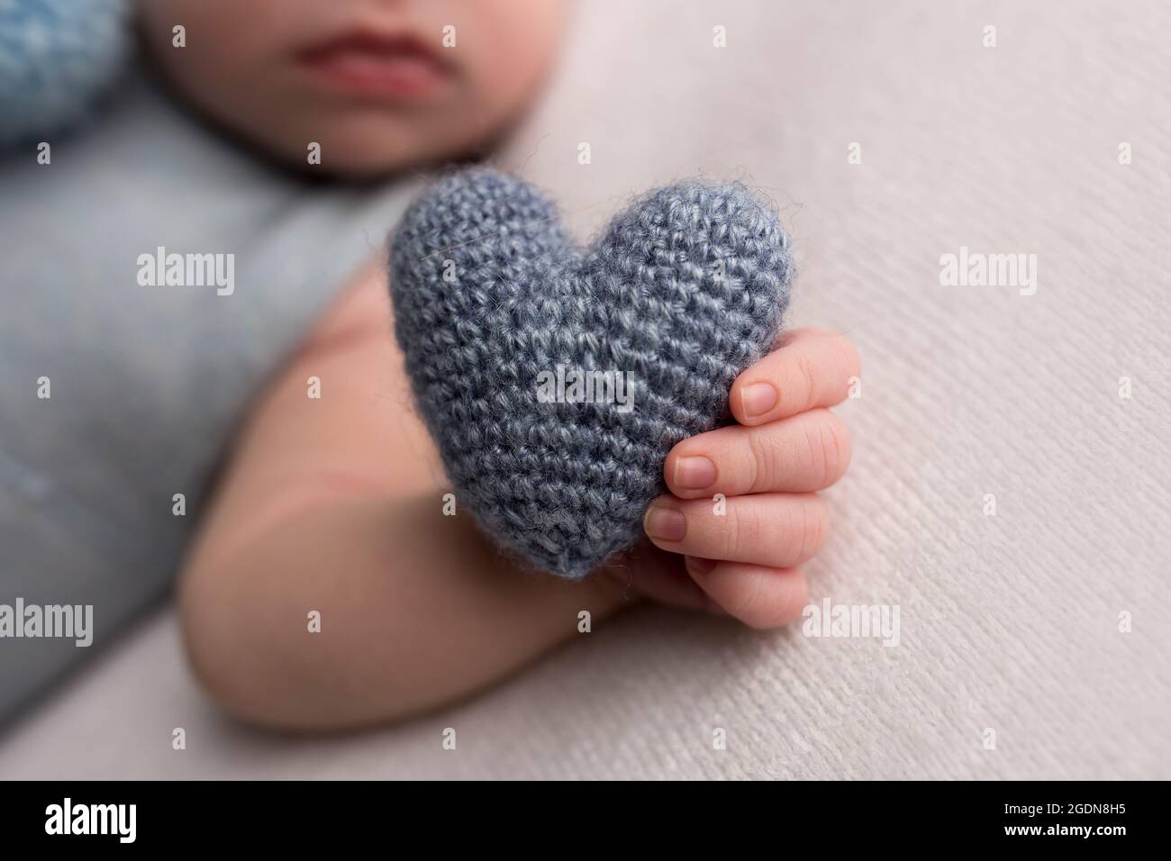 Happy newborn baby hold soft grey heart  Stock Photo