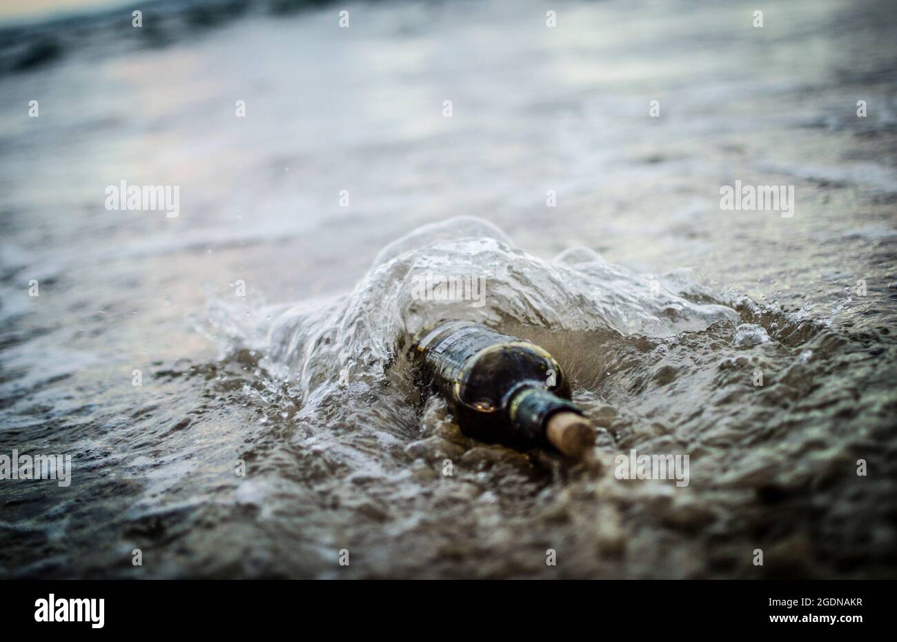 Message in a bottle - a bottle half buried in sand on a beach Stock Photo