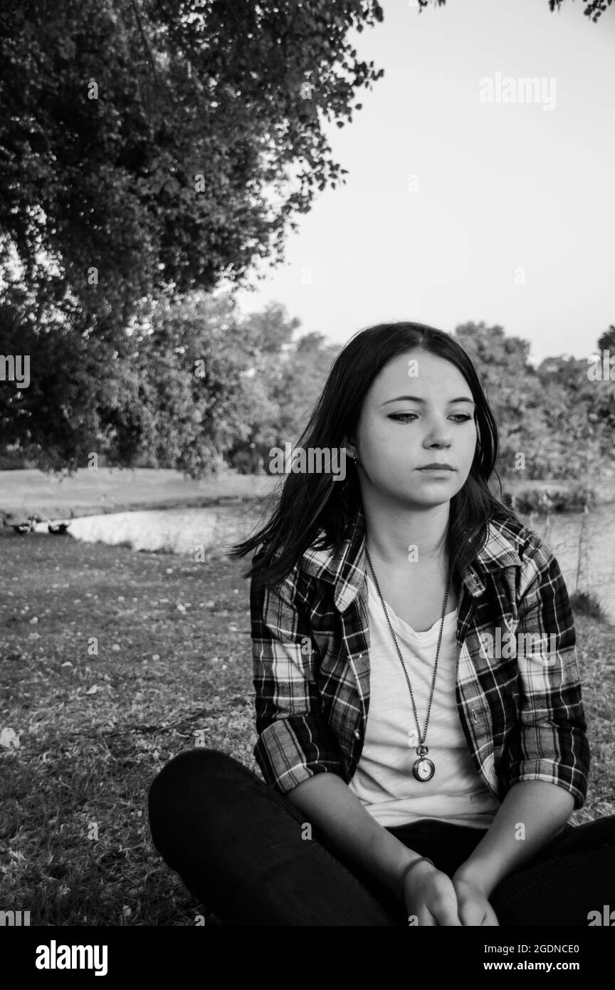 moody image of a young 25 year old woman alone in a park Stock Photo