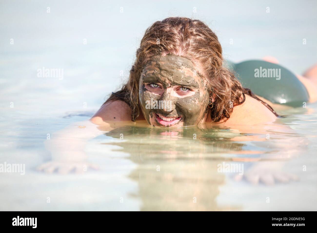 Mud covered Caucasian tourist floats in the Dead Sea, Israel Stock Photo