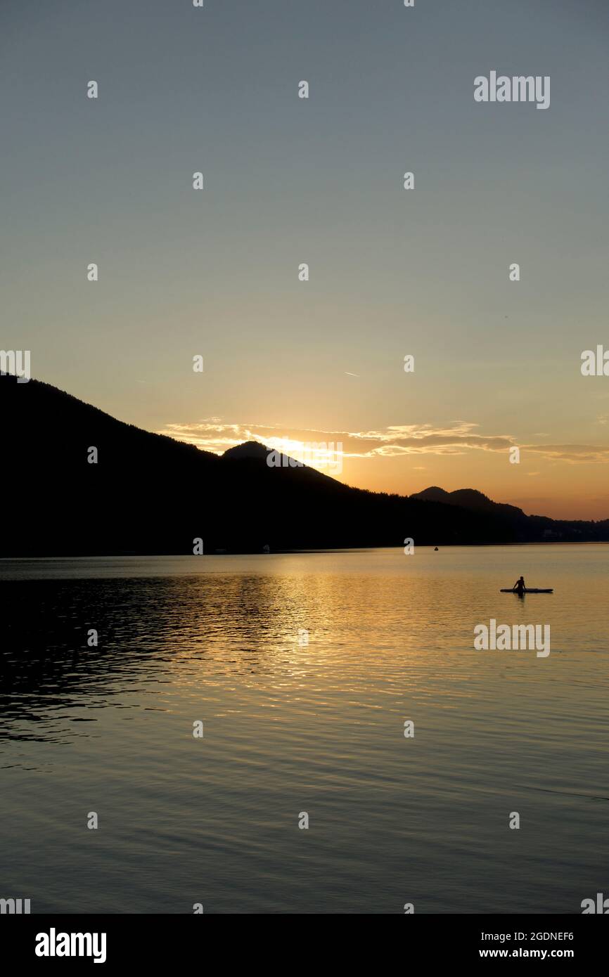 Remains of the day at the lake. Sun going down behind silhouetted mountains in Austria. Portrait landscape, Fuschl lake, Fuschl am See Stock Photo