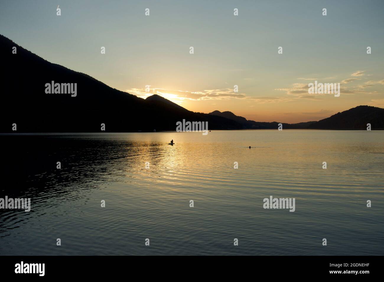 Peaceful lake horizon at sunset with late evening swimmers having a last swim in clear Alpine water, Fuschl lake, Fuschl am See, Austria Stock Photo