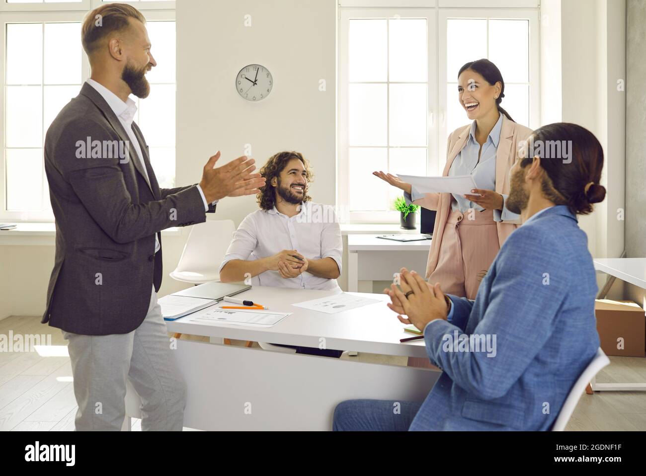 Group of male colleagues applauding happy woman for presentation in business meeting Stock Photo