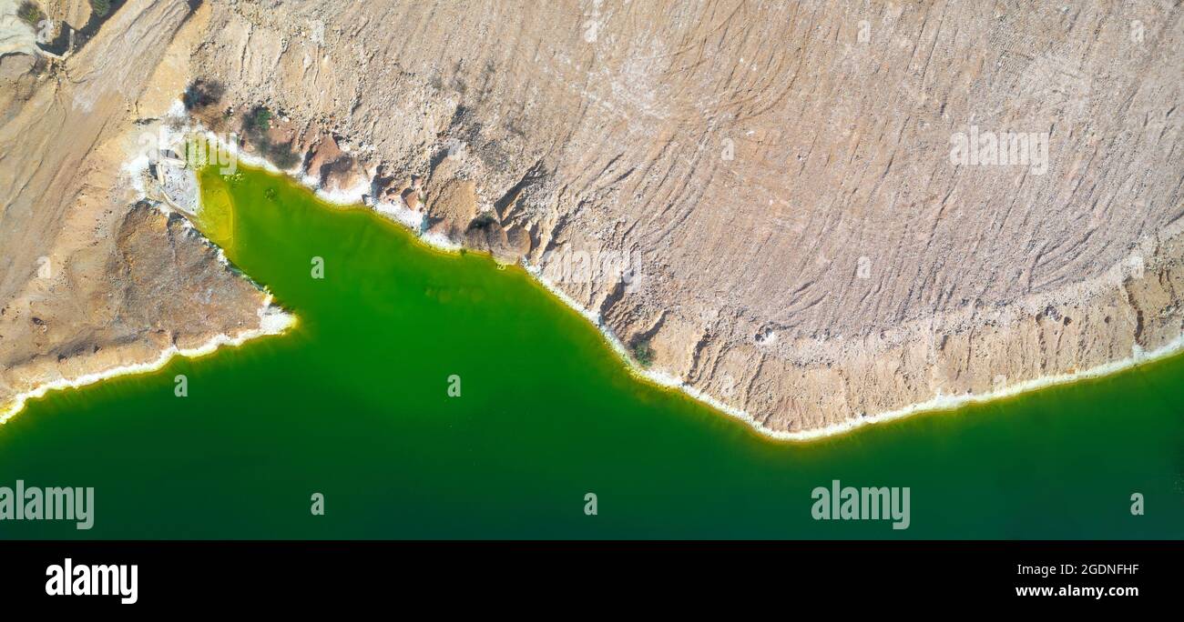 Shore of toxic green lake in abandoned open pit copper mine. its color derives from high levels of acid and heavy metals. Aerial panorama from directl Stock Photo