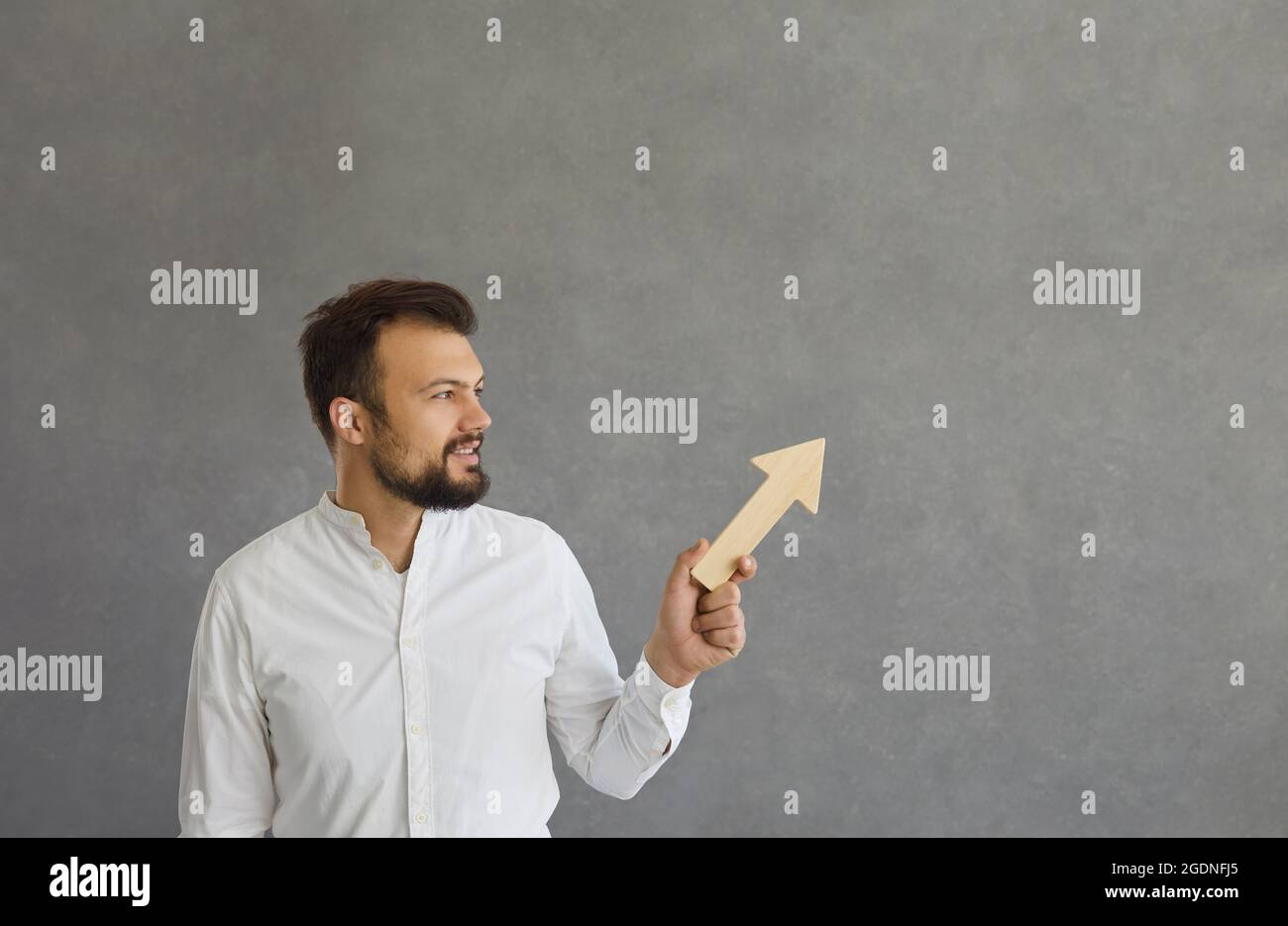 Man holds a wooden arrow in his hands, which points upwards and symbolizes the achievement of goals. Stock Photo