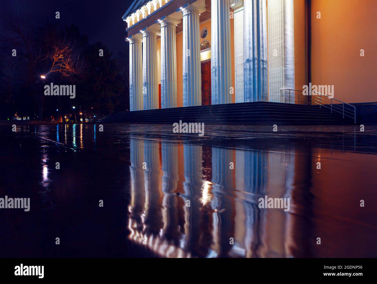 Doric columns of cathedral . Architecture of cathedral reflected in the wet pavement . Rainy night in the city Stock Photo