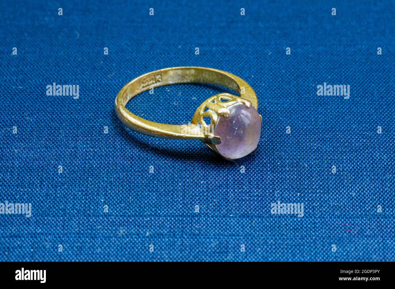 An old gold ring with amethyst on a blue mat, selected focus Stock Photo