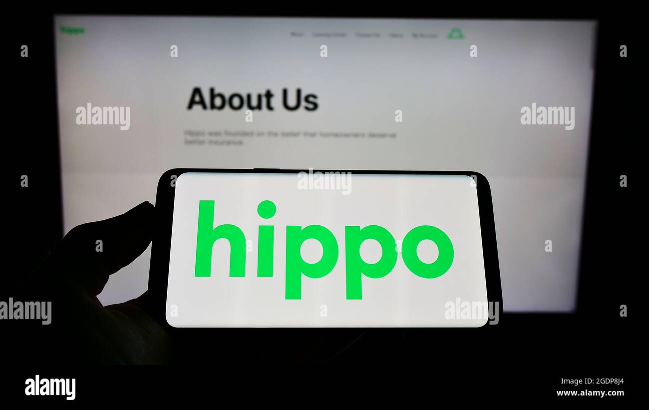 Person holding mobile phone with logo of US insurance company Hippo