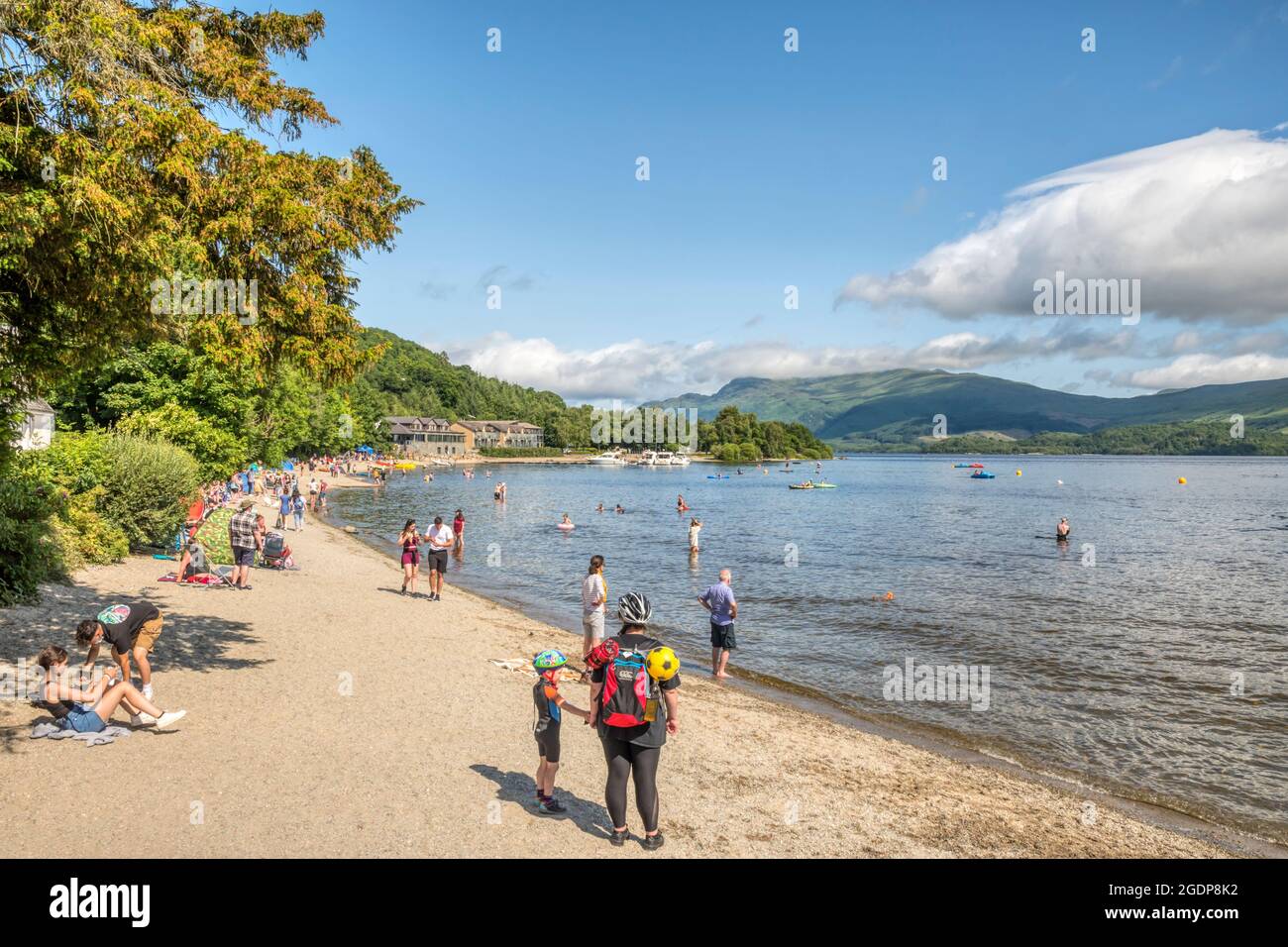 People on beach at Luss beside Loch Lomond. With Lodge on Loch Lomond and Ben Lomond in background. Stock Photo