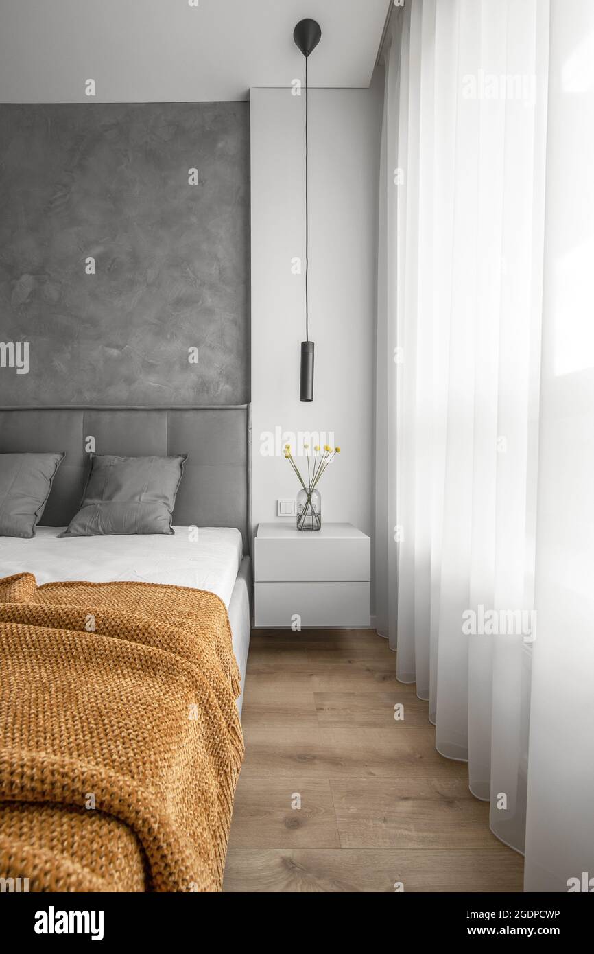 Modern Minimalism Style Bedroom Interior with grey wall and yellow flowers on bedside table Stock Photo