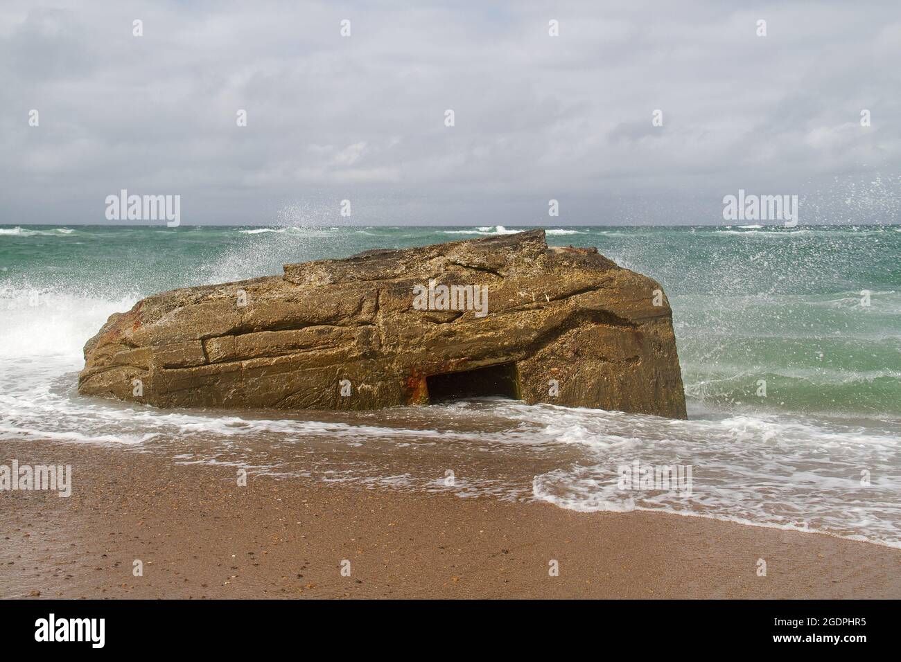 Waves splash against a German bunker from the second world war, fallen from te dunes in the sea in the Tannis Bugt in Denmark Stock Photo