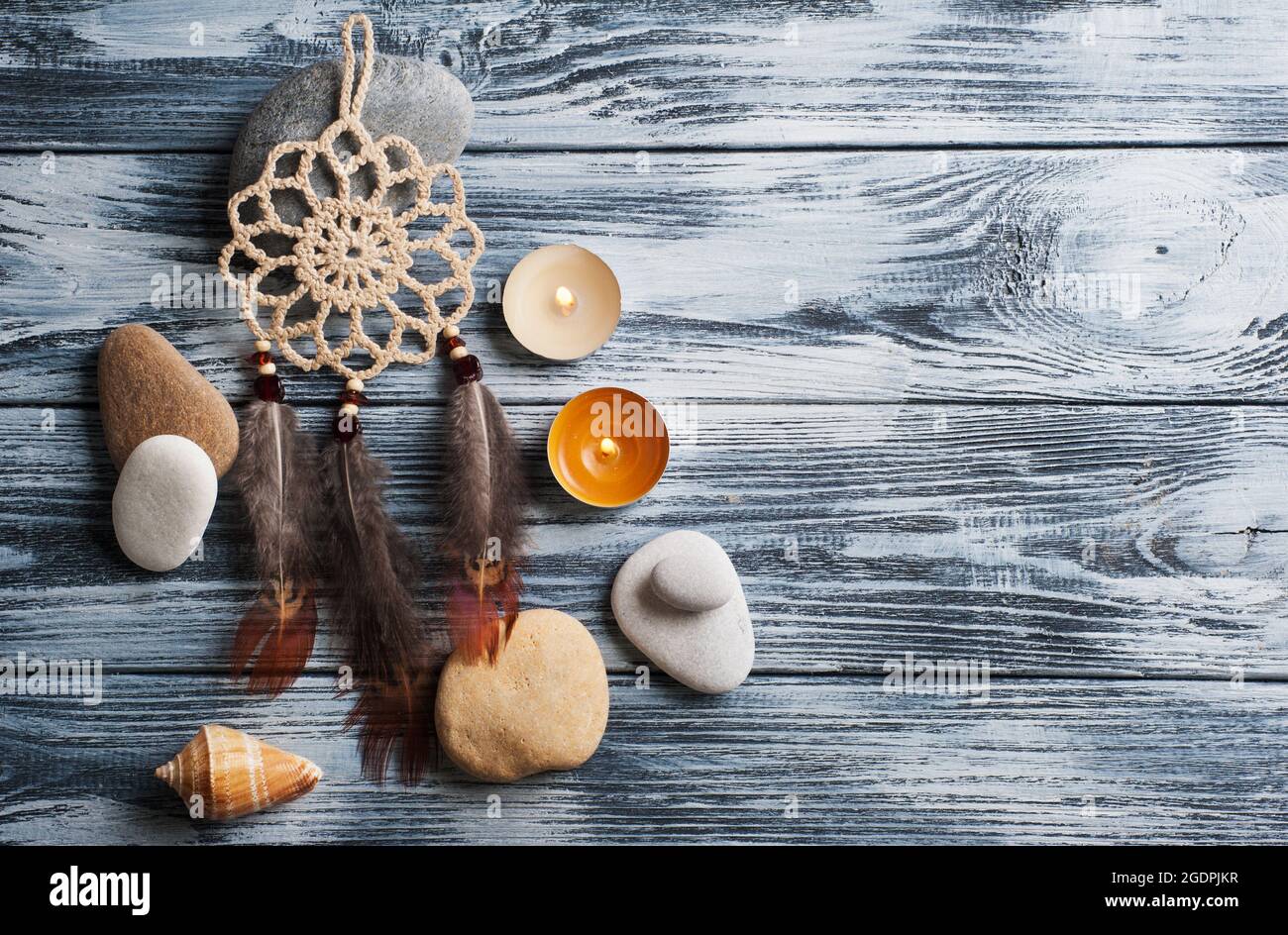Spa background with stones and lit candles on weathered wooden table