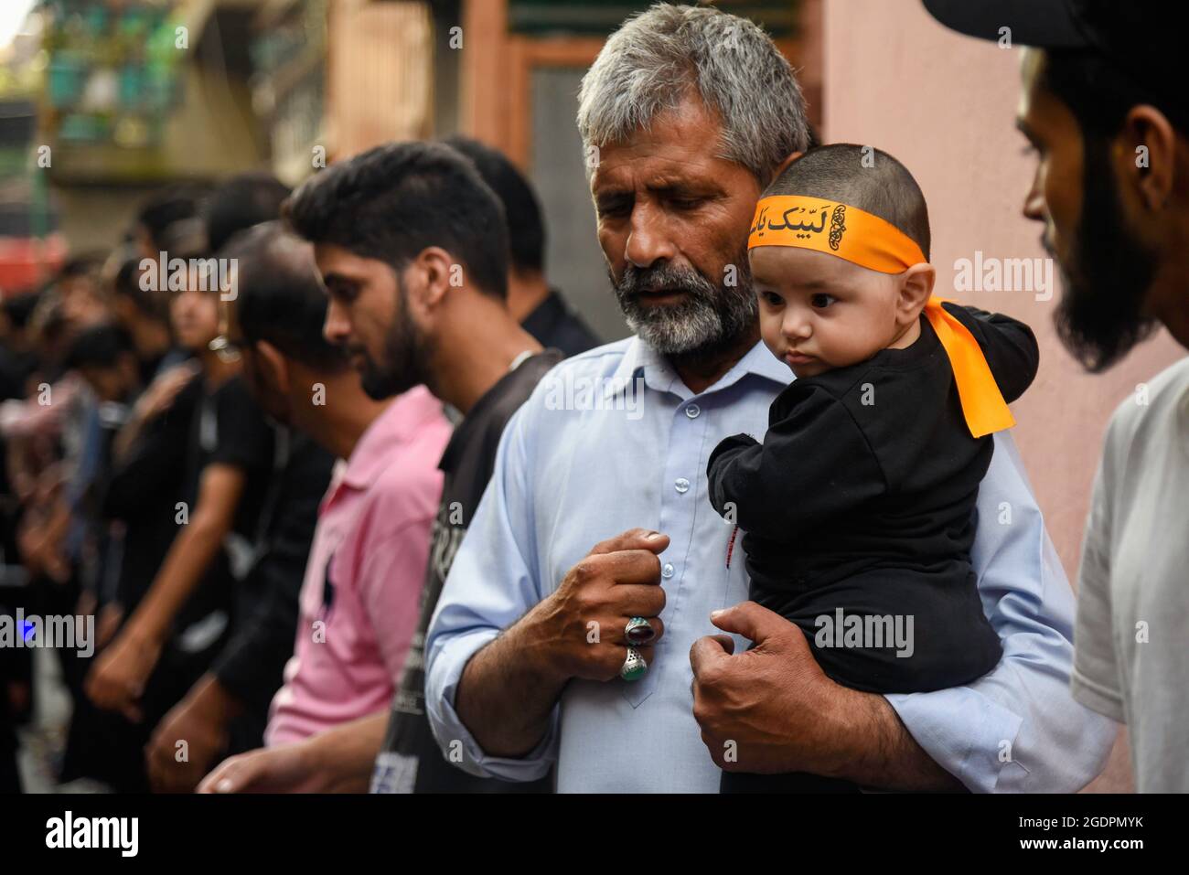 Srinagar, India. 14th Aug, 2021. A Kashmiri Shia man carries a kid ...
