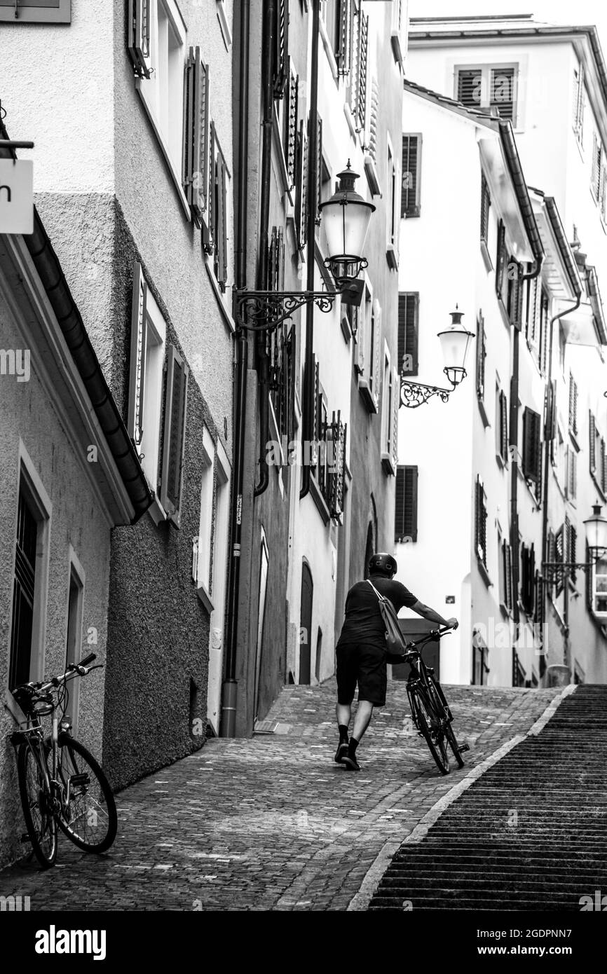 Rear view of a man pushing his bike on the hill in the down town Stock Photo