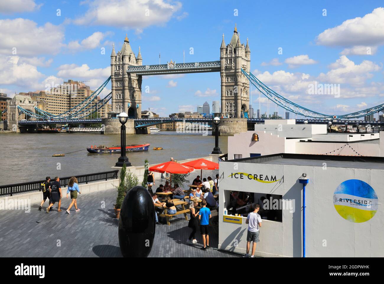 The summer Riverside Terrace on the banks of the River Thames, with iconic Tower Bridge beyond, in London, UK Stock Photo