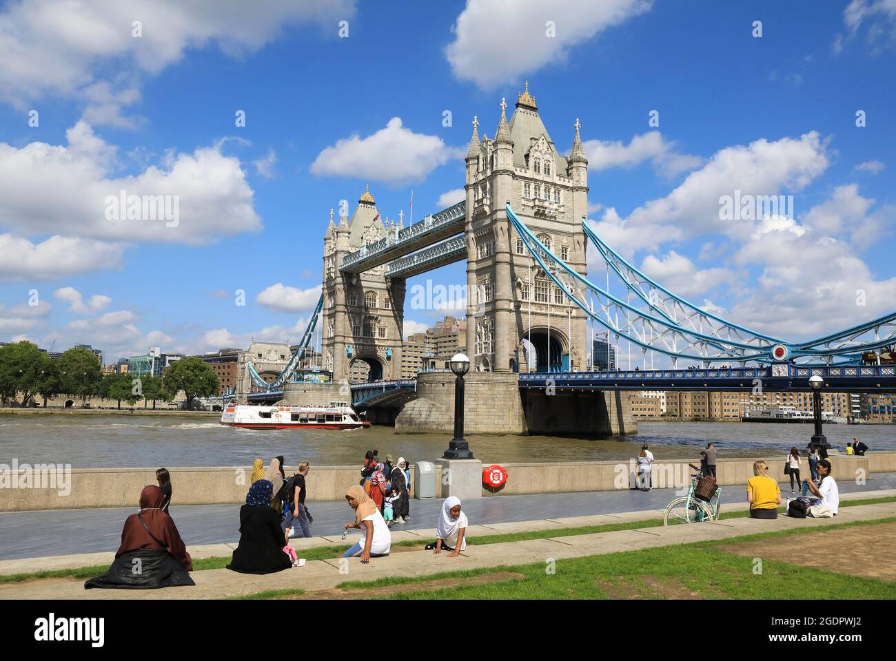 Tourists by Tower Bridge over the River Thames, from Potters Field Park
