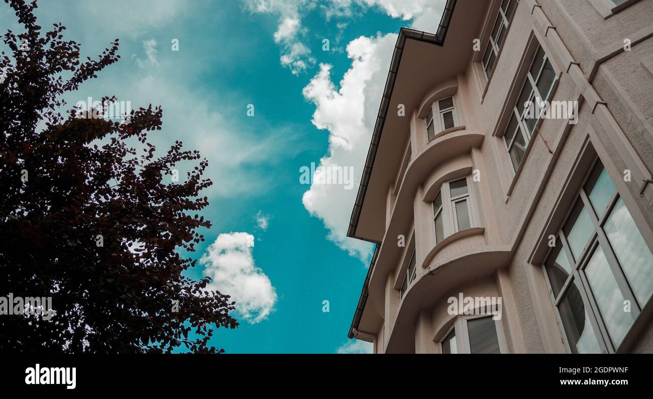 white building and tree under the blue cloudy sky, white clouds, teal sky Stock Photo