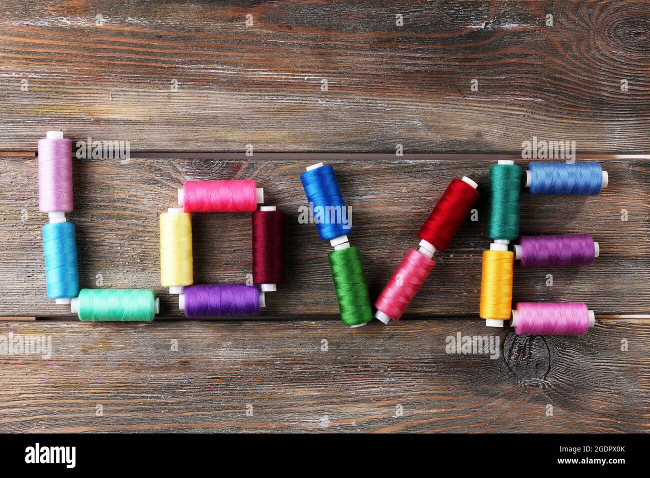 Love word formed with colorful threads on wooden background Stock Photo ...