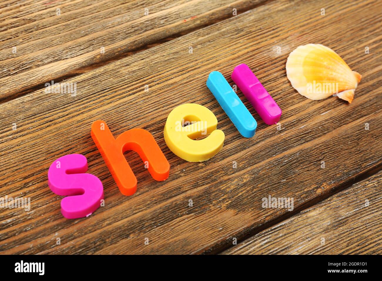 Shell word formed with colorful letters on wooden background Stock