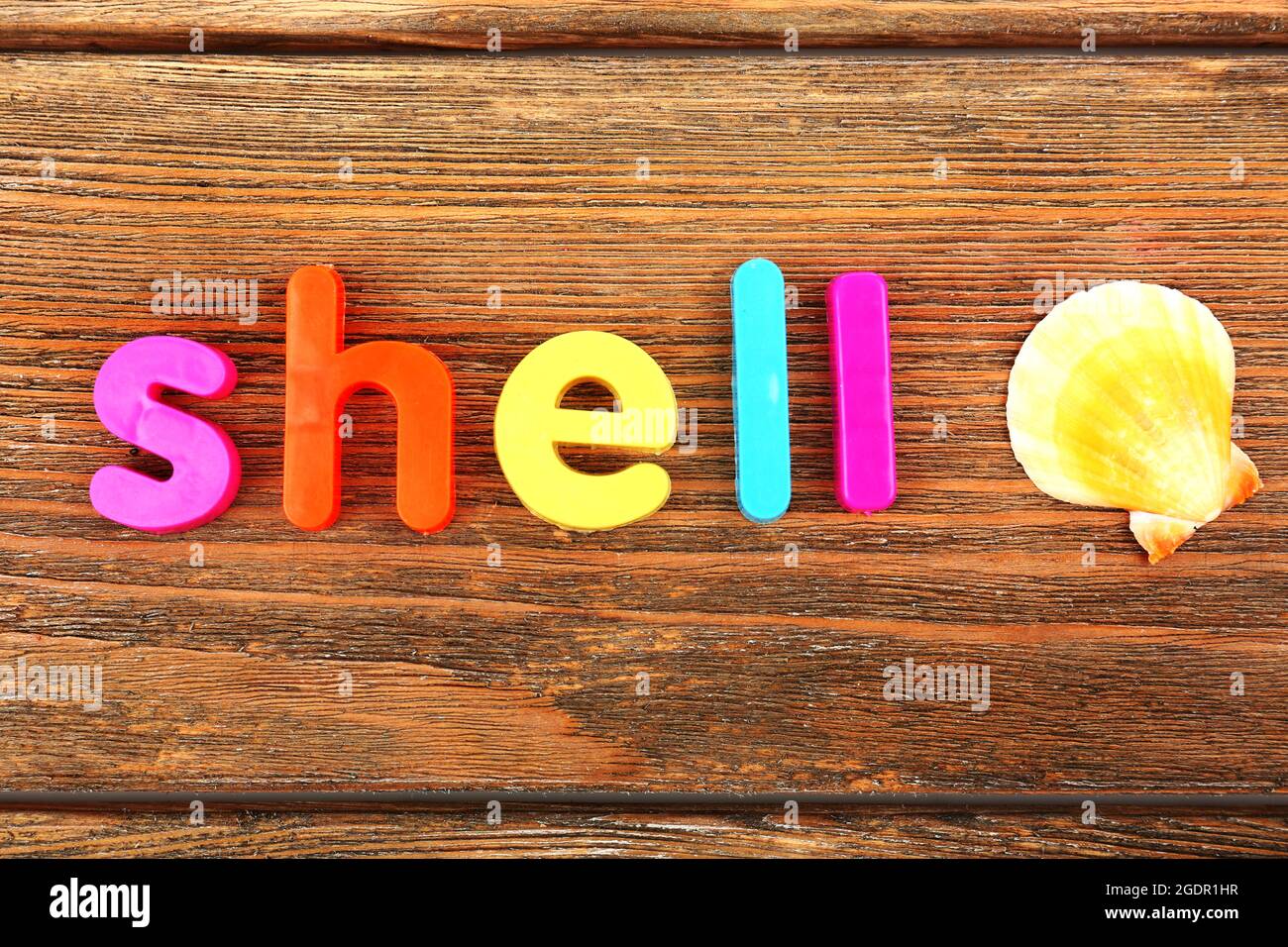 Shell word formed with colorful letters on wooden background Stock