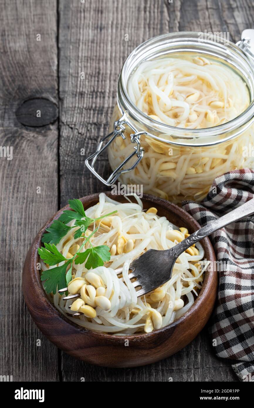 Marinated  sprouted mung beans in glass jar on wooden table Stock Photo