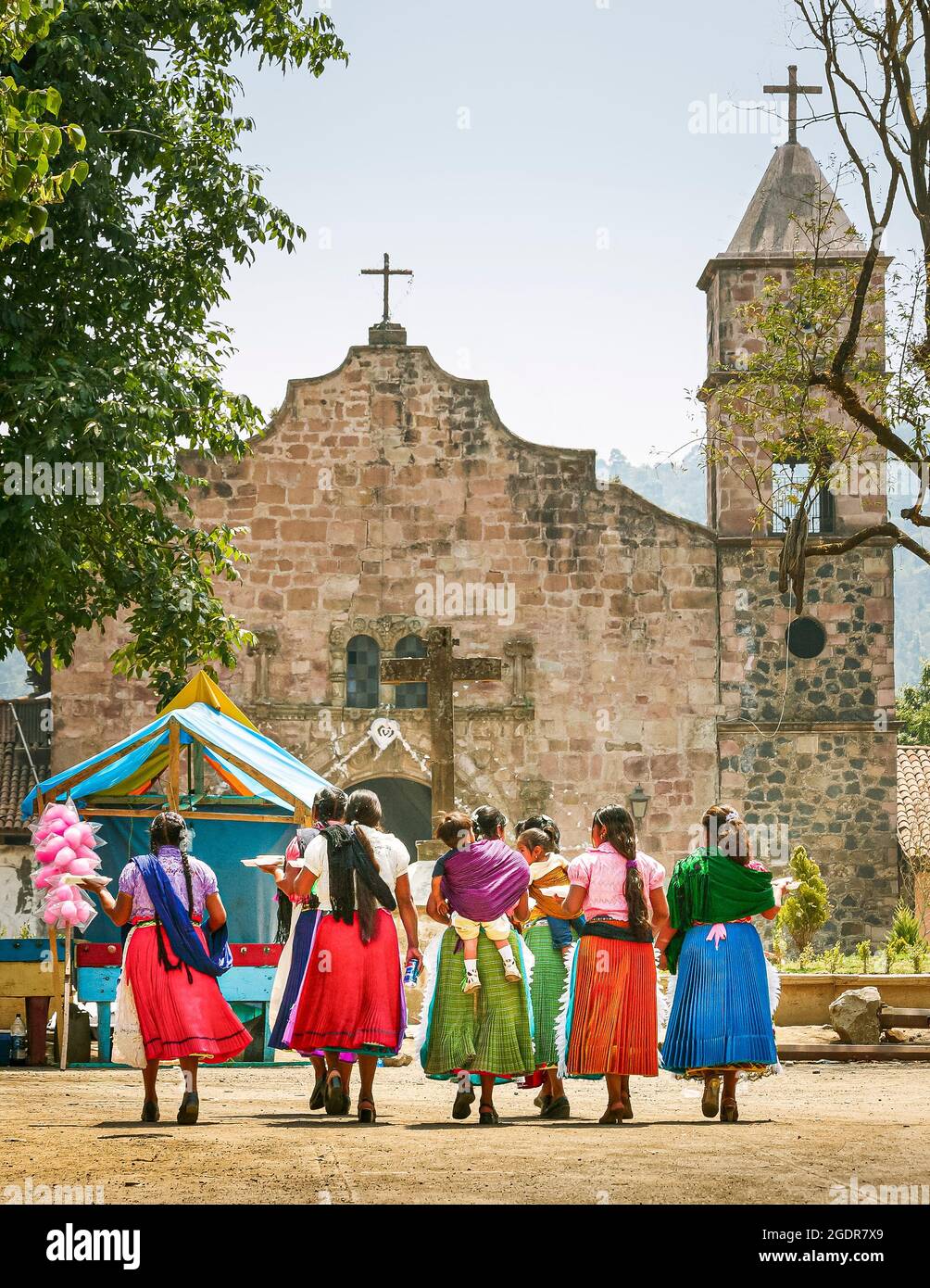 A group of colorfully dressed Purepecha women walk towards the town temple in Capacuaro, Michoacan, Mexico. Stock Photo