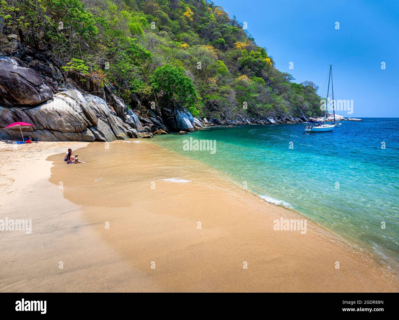 A couple enjoys fresh coconuts at Colomitos Beach, a hidden gem of azure water just south of Puerto Vallarta, Mexico. Stock Photo