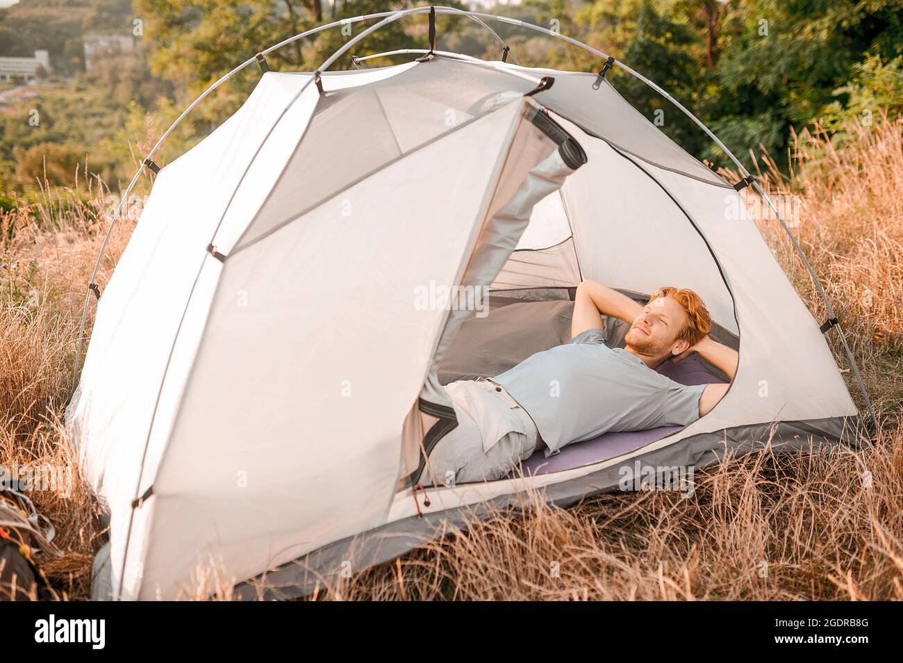 Time to sleep. A man laying in his tent and feeling sleepy Stock Photo