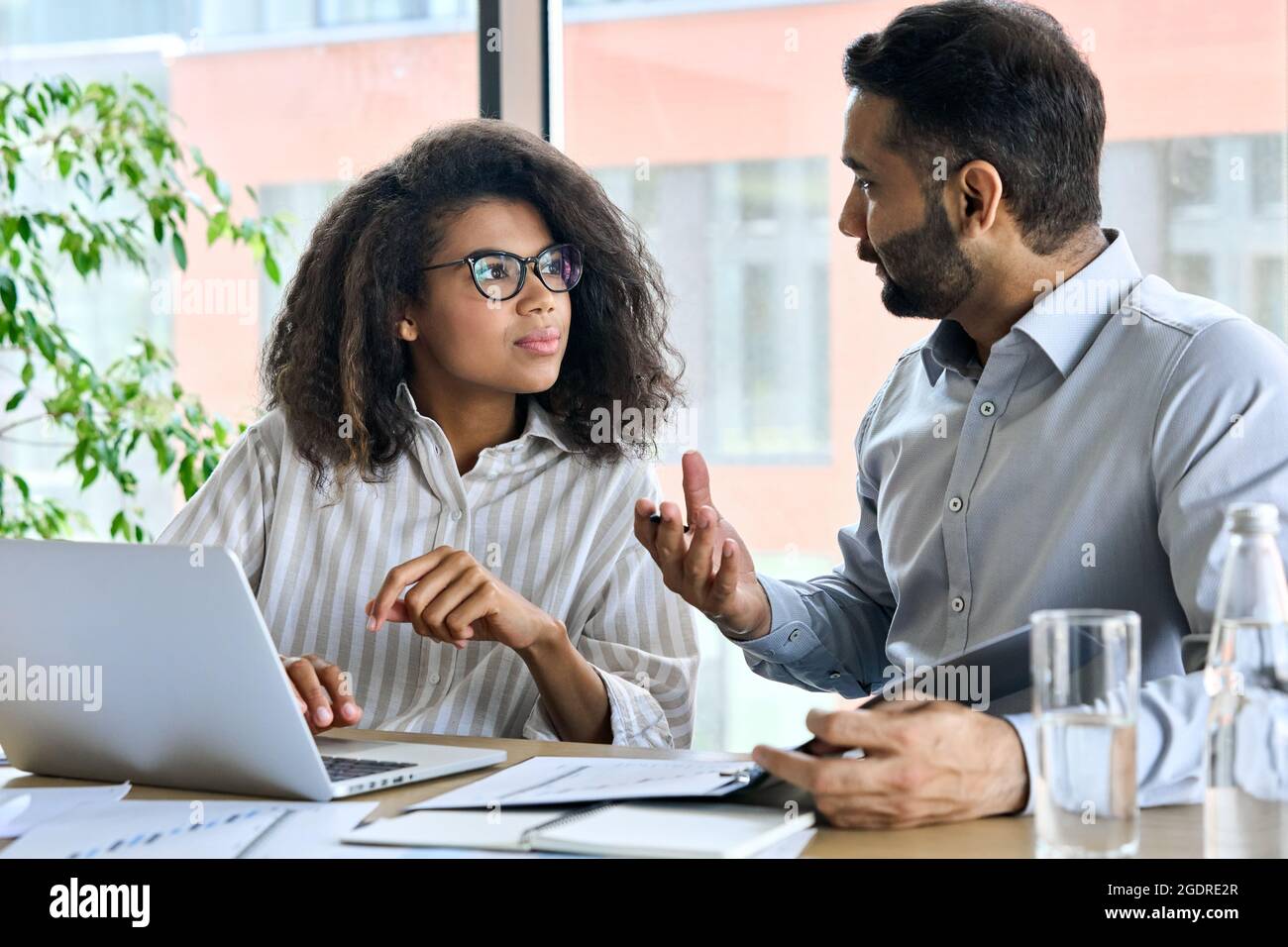 Indian ceo mentor leader talking to female trainee using laptop at meeting. Stock Photo