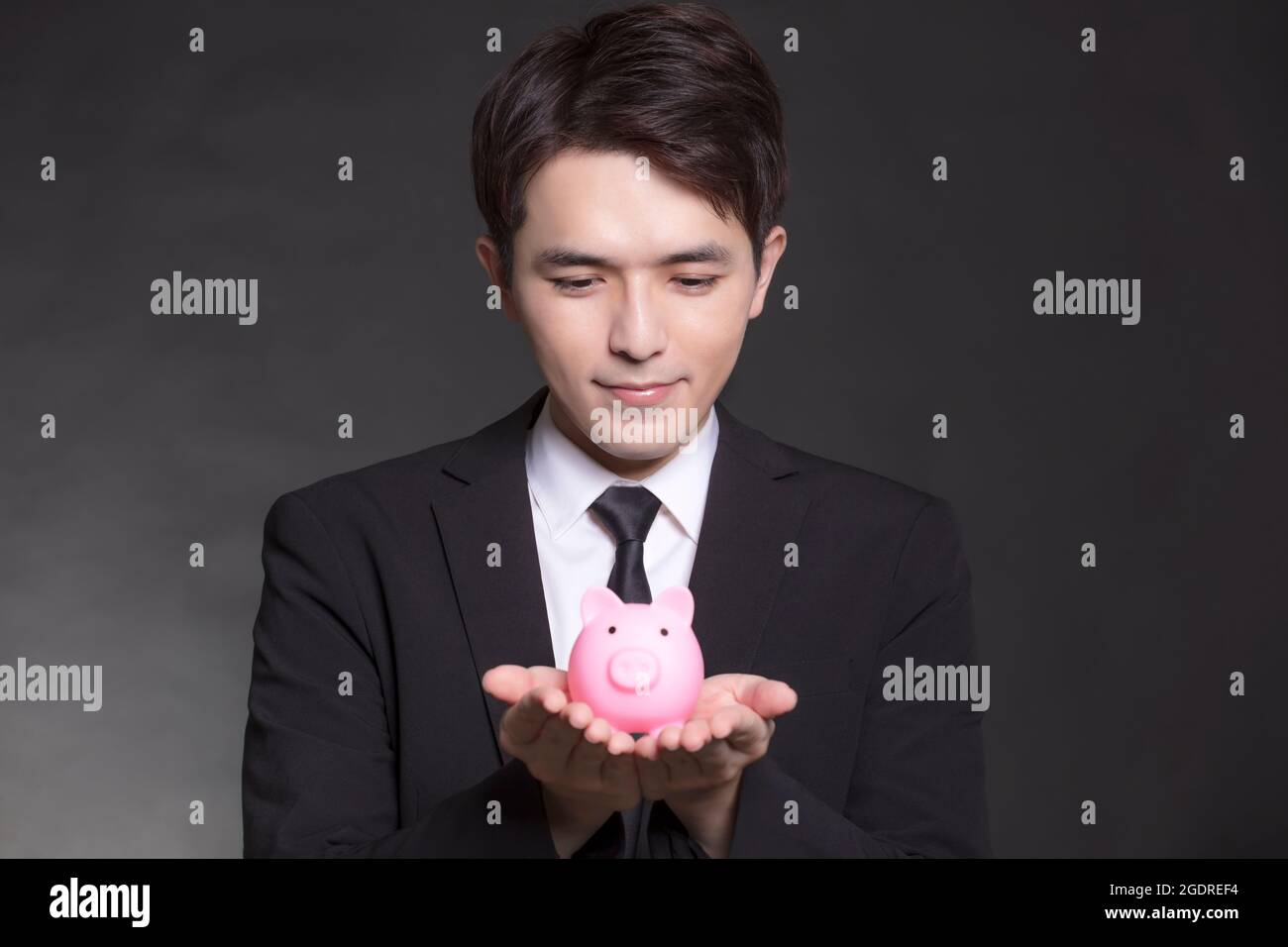 Business man in black suit and holding pink piggy bank Stock Photo - Alamy