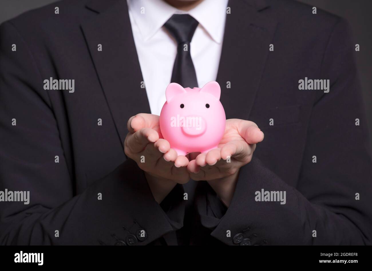 Business man in black suit and holding pink piggy bank Stock Photo - Alamy